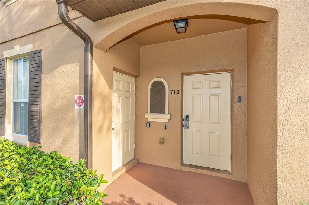 The exterior entrance of a building features two beige doors, a small window, and a light — 712 CALABRIA AVENUE, DAVENPORT, FL