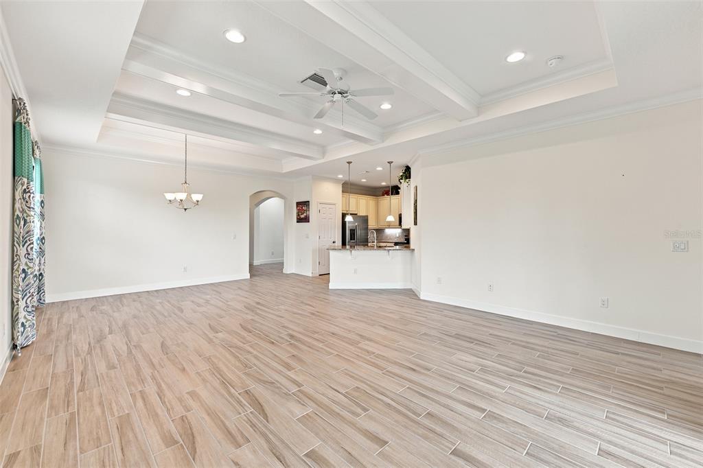 A spacious living room features tile flooring, a coffered ceiling, and an open kitchen area — 623 CHIPPER DRIVE, SUN CITY CENTER, FL