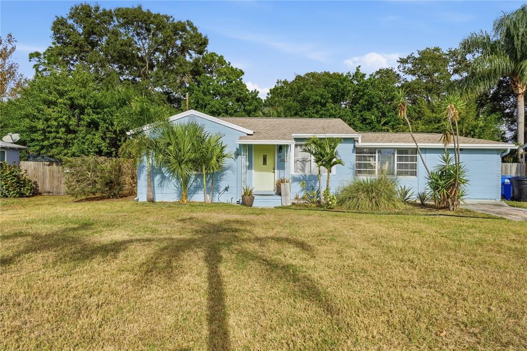 A light blue single-story house with a pale yellow front door and palm trees — 1249 ESSEX DRIVE N, ST PETERSBURG, FL
