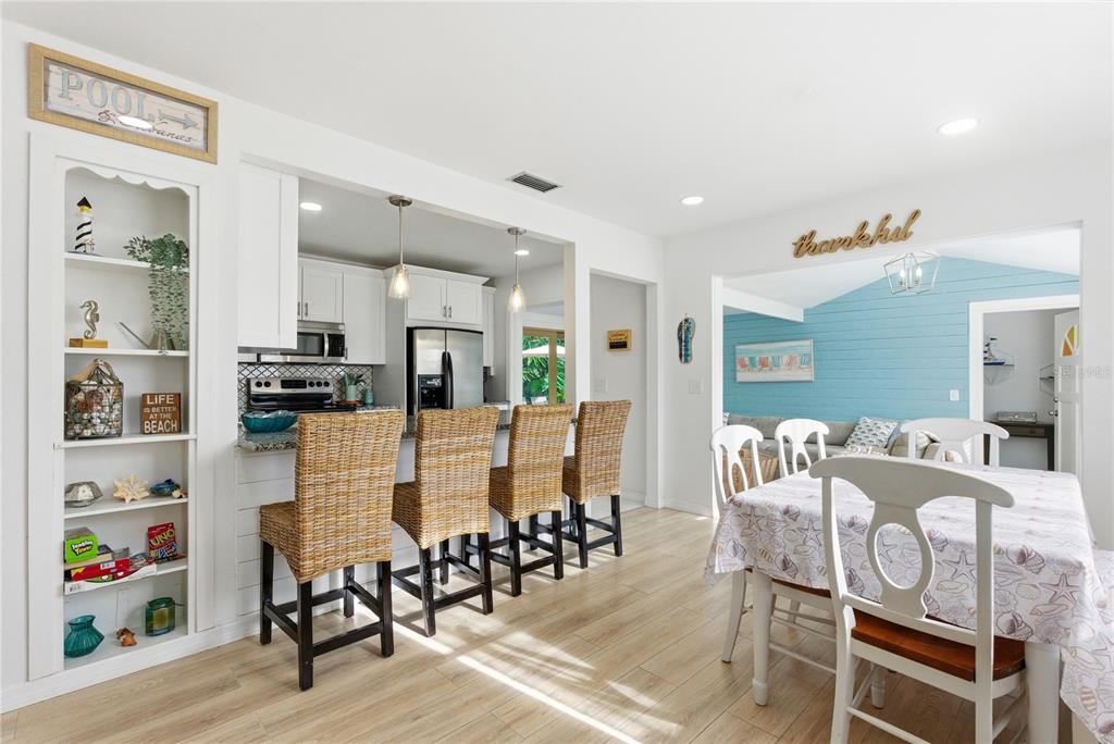 A kitchen with a breakfast bar and stools opens into a dining area with blue walls — 1249 ESSEX DRIVE N, ST PETERSBURG, FL