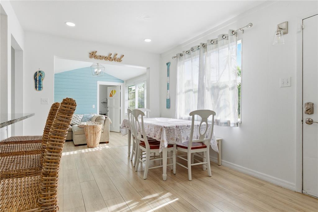A dining area with a table and chairs leads into a living room with blue walls — 1249 ESSEX DRIVE N, ST PETERSBURG, FL