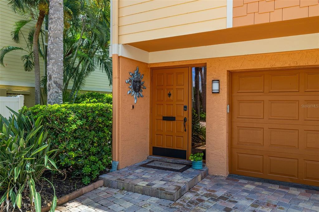 The exterior of a home features a brown front door, a garage, and landscaping — 533 SANDY HOOK ROAD, TREASURE ISLAND, FL