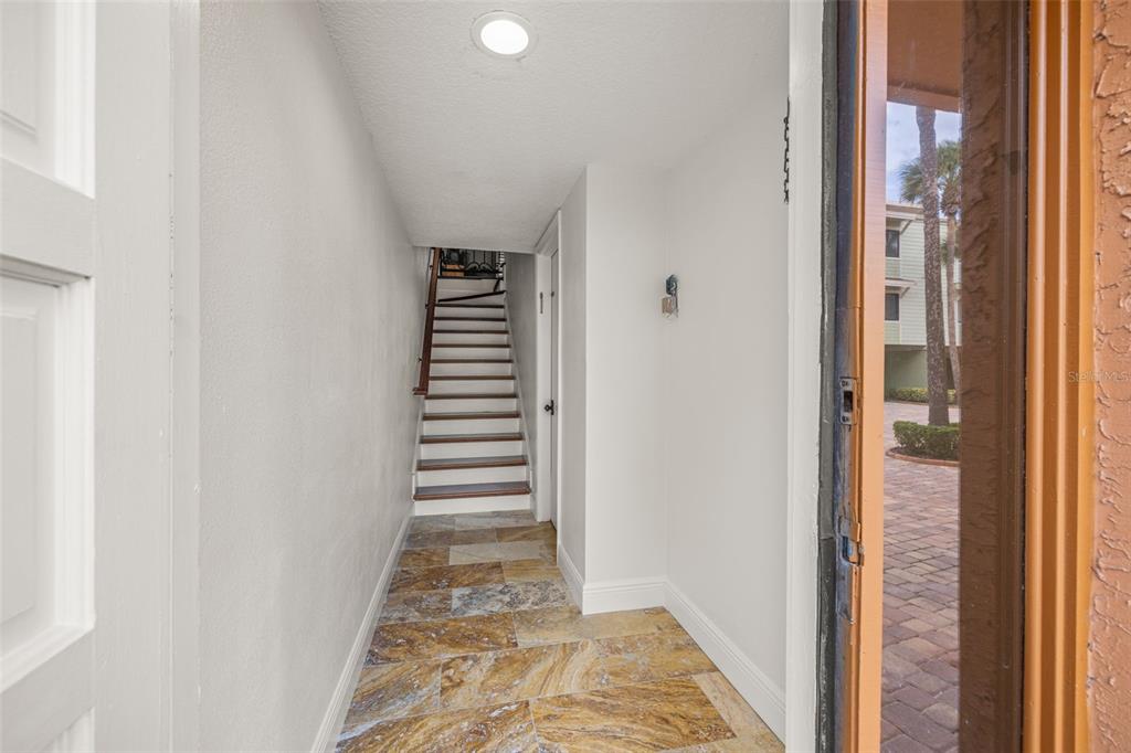 An entryway features stone tile flooring, white walls, and a staircase leading to an upper level — 533 SANDY HOOK ROAD, TREASURE ISLAND, FL