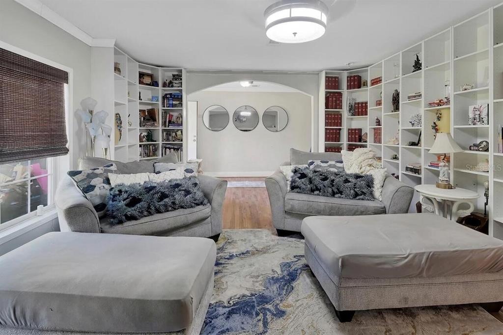 A living room features two gray sofas, two ottomans, built-in bookshelves, and three circular mirrors — 369 GARDEN LANE, BUNNELL, FL