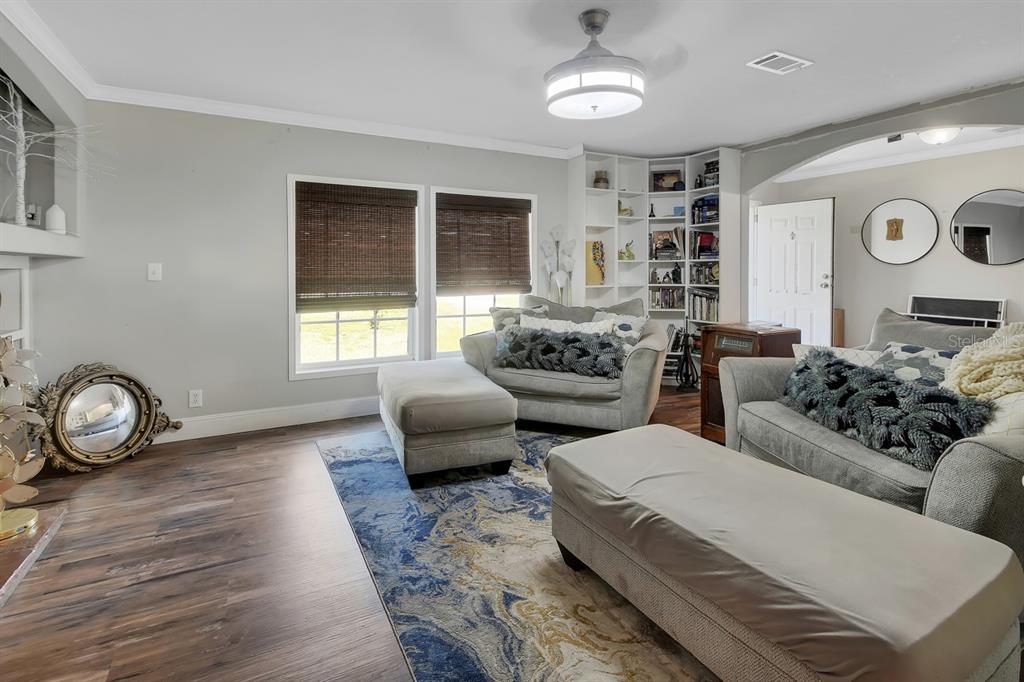 A living room features gray furniture, a blue and gold area rug, and built-in shelving — 369 GARDEN LANE, BUNNELL, FL