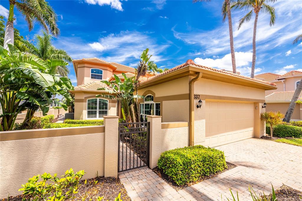 A two-story stucco house features a tile roof, a garage, and a gated courtyard entrance — 3337 SUNSET KEY CIRCLE, PUNTA GORDA, FL