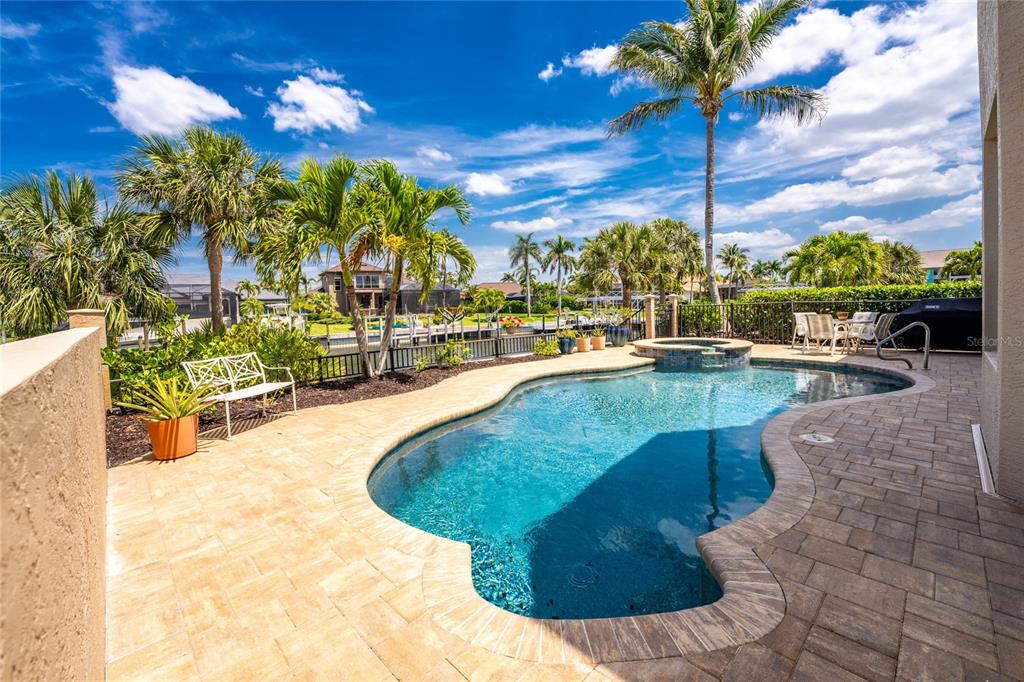 A backyard swimming pool with a spa, patio, and palm trees overlooks a canal — 3337 SUNSET KEY CIRCLE, PUNTA GORDA, FL