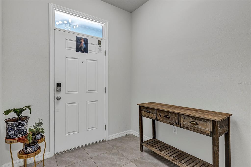 An entryway features a white door with a transom window, tile flooring, and a console table — 4015 BLUE BANKS LANE, BRADENTON, FL