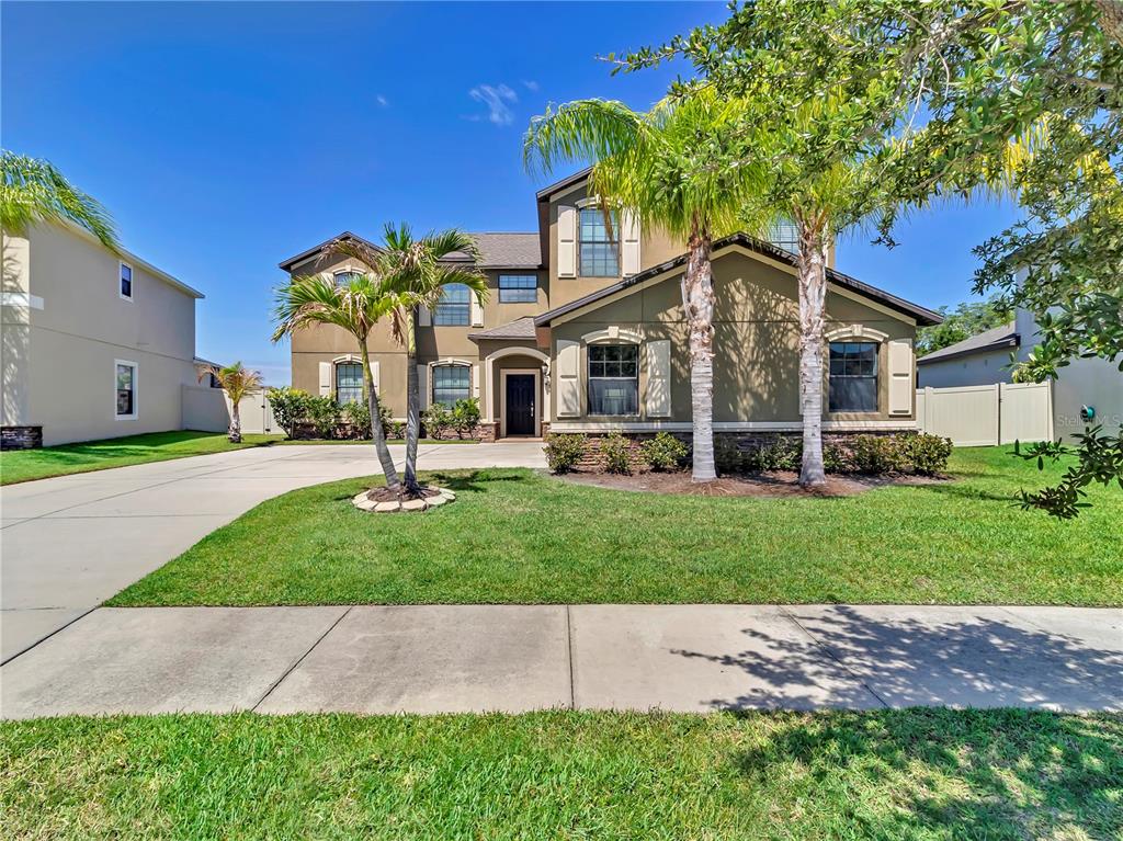 A swimming pool with steps sits inside a screened enclosure overlooking a pond and trees — 5063 IVORY STONE DRIVE, WIMAUMA, FL