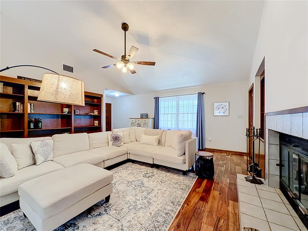 A living room features a white sectional sofa, a fireplace, and built-in wooden bookshelves — 7104 BLEDSOE AVENUE, ORLANDO, FL