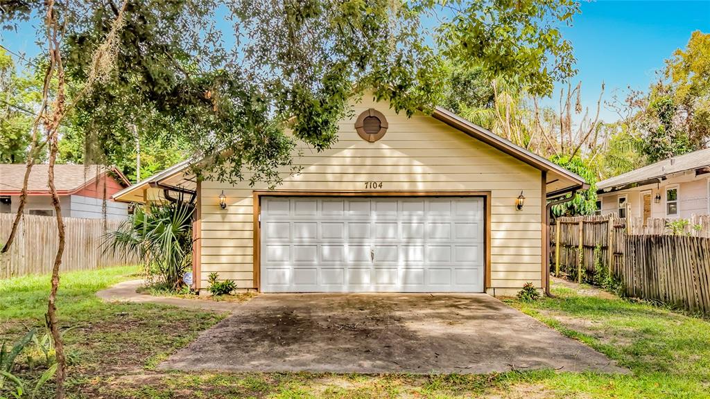 A detached garage with light-colored siding and a white sectional door sits on a lot — 7104 BLEDSOE AVENUE, ORLANDO, FL
