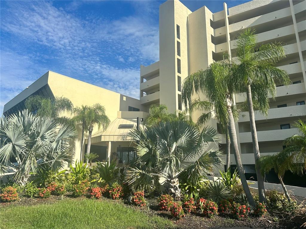A multi-story beige building with palm trees and landscaping in the foreground — 6009 SEA RANCH DRIVE UNIT 507, HUDSON, FL