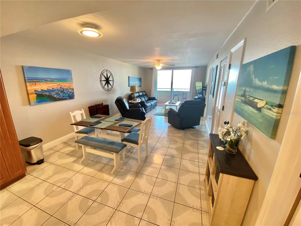 An open-concept living and dining area features tiled floors, a dining set, and seating furniture — 6009 SEA RANCH DRIVE UNIT 507, HUDSON, FL