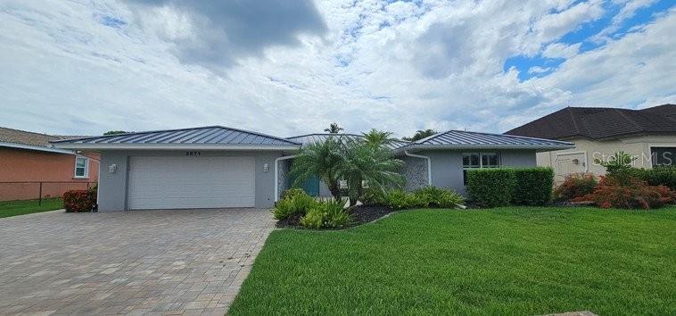 A single-story house with a metal roof, a two-car garage, and a paved driveway — 2871 CORAL WAY, PUNTA GORDA, FL