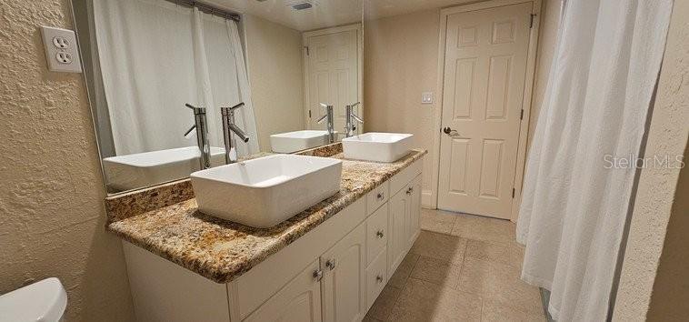 A bathroom features a double vanity with vessel sinks, granite countertops, and a large mirror — 2871 CORAL WAY, PUNTA GORDA, FL