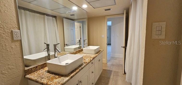 A bathroom features a double vanity with vessel sinks, granite countertops, and a large mirror — 2871 CORAL WAY, PUNTA GORDA, FL