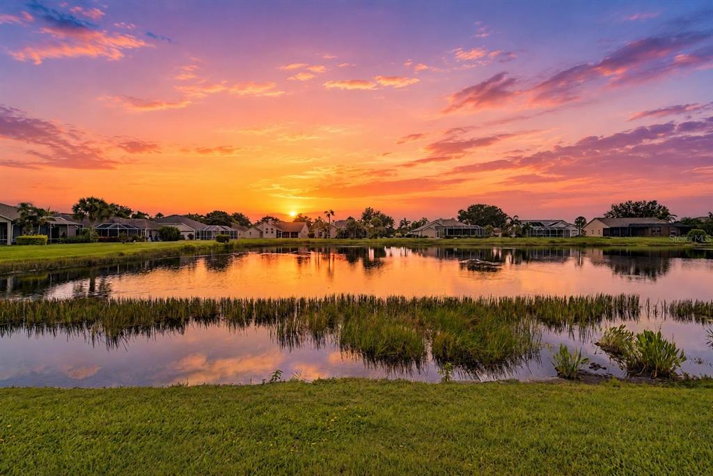 A sunset view over a pond with surrounding houses and grassy landscaping — 2815 89TH AVENUE E, PARRISH, FL