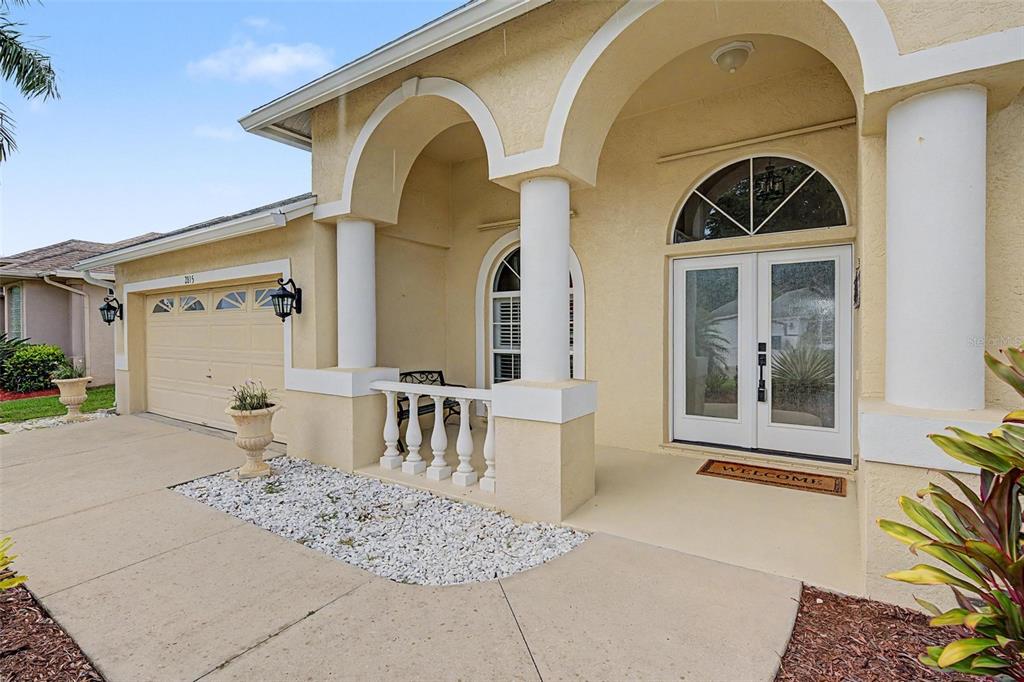 The exterior of a beige house features a covered entryway with white columns and arches — 2815 89TH AVENUE E, PARRISH, FL