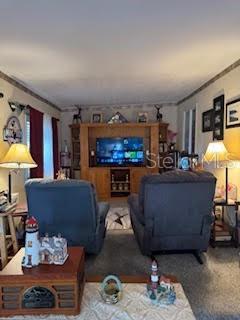 A living room features two gray recliners facing a large wooden entertainment center with a television — 9000 US HIGHWAY 192 UNIT 975, CLERMONT, FL