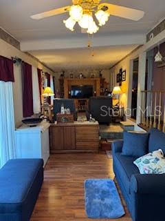 A living room features wood-look flooring, a blue sofa, a ceiling fan, and wooden cabinetry — 9000 US HIGHWAY 192 UNIT 975, CLERMONT, FL