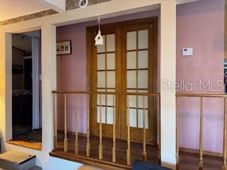A wooden railing separates a room with pink walls and French doors from a lower level — 9000 US HIGHWAY 192 UNIT 975, CLERMONT, FL