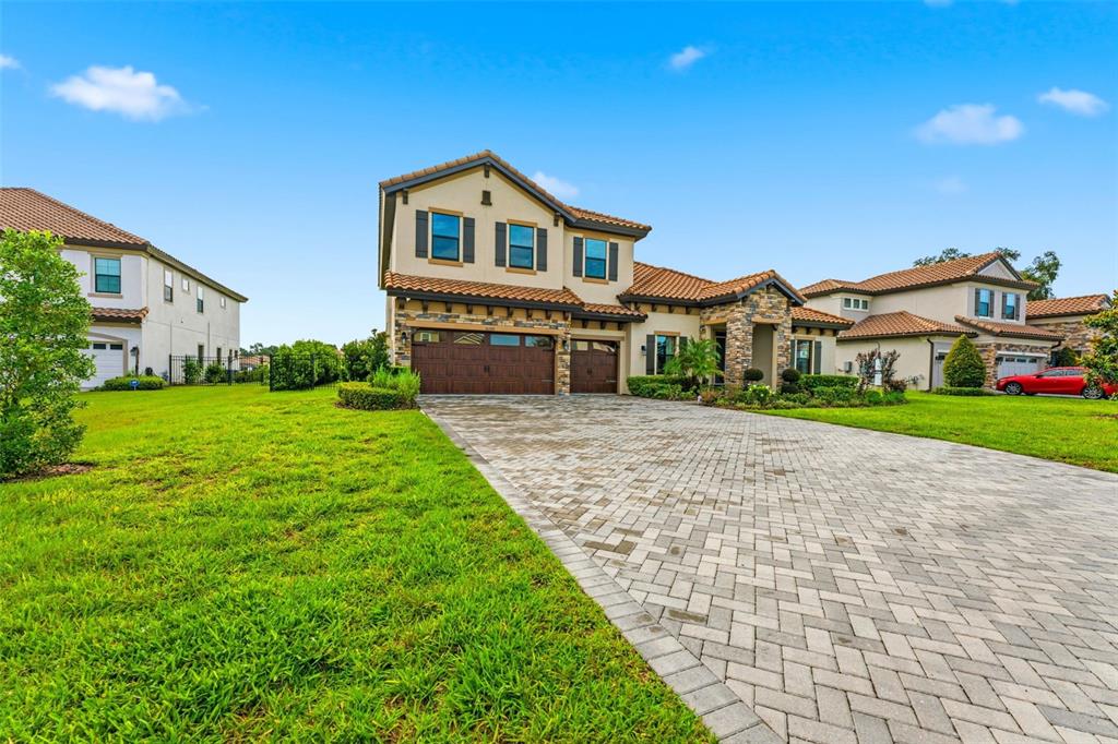 A two-story suburban house with a stone facade, tile roof, and a paved driveway — 10370 MEADOWRUN DRIVE, LITHIA, FL