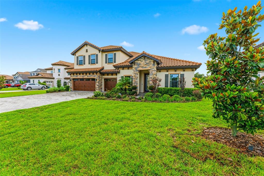 A two-story house with a stone facade, tile roof, and a paved driveway — 10370 MEADOWRUN DRIVE, LITHIA, FL