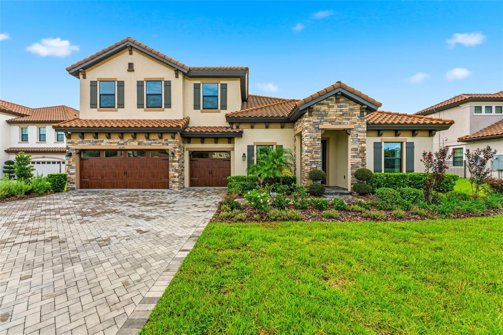 A two-story suburban house with a stone facade, tile roof, and a paved driveway — 10370 MEADOWRUN DRIVE, LITHIA, FL