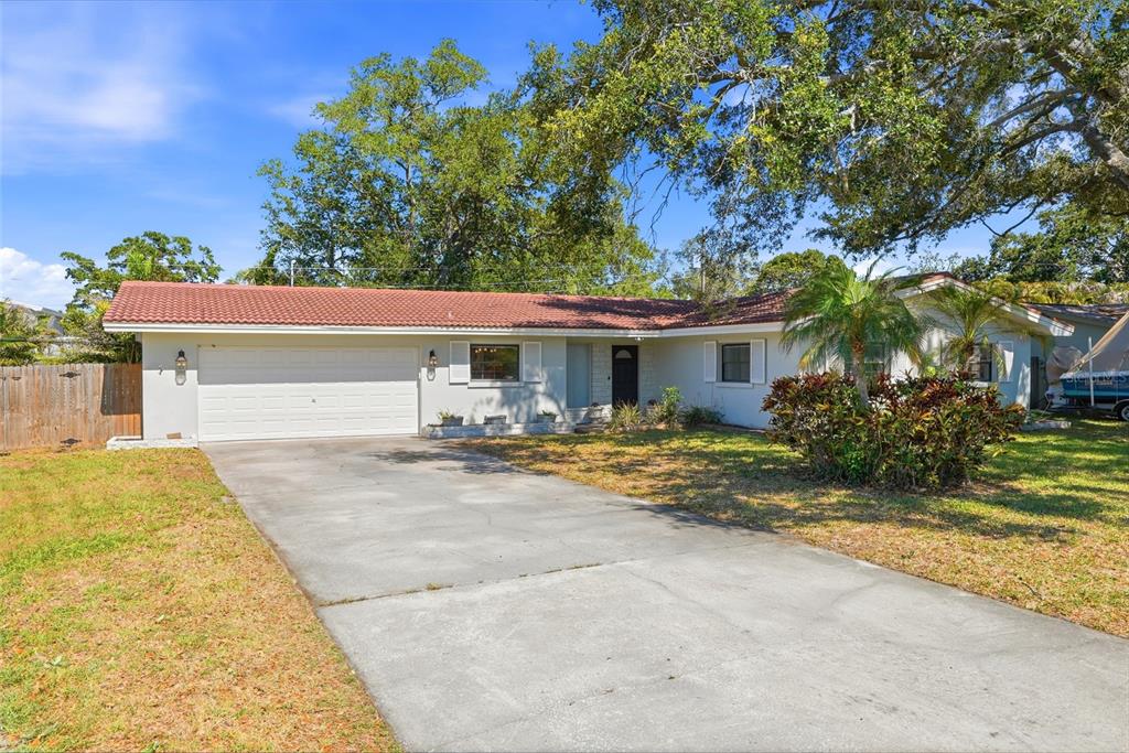 A single-story house with a white exterior, red tile roof, and a concrete driveway — 1349 VIEWTOP DRIVE, CLEARWATER, FL