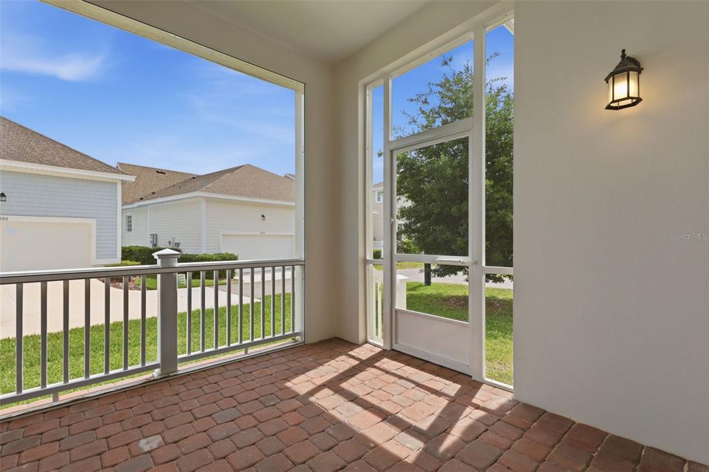 A screened-in porch features brick flooring, a white railing, and a door leading outside — 7410 BARRIER COVE WAY, CELEBRATION, FL