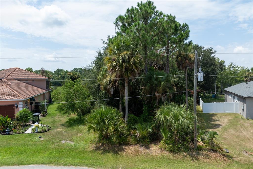 An aerial view shows a vacant, tree-covered lot situated between two residential houses — 45 LUTHER DRIVE, PALM COAST, FL