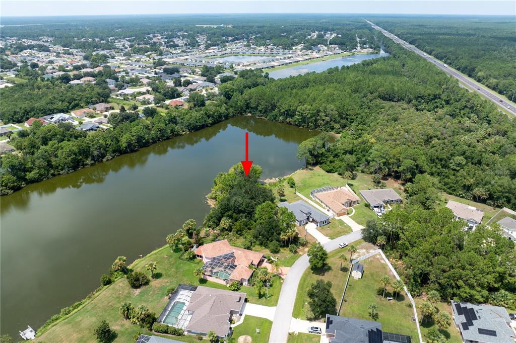 An aerial view shows a wooded vacant lot situated along the edge of a lake — 45 LUTHER DRIVE, PALM COAST, FL