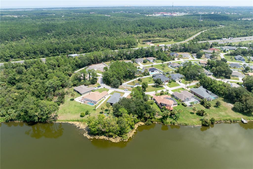 An aerial view shows several houses with swimming pools situated along the edge of a lake — 45 LUTHER DRIVE, PALM COAST, FL
