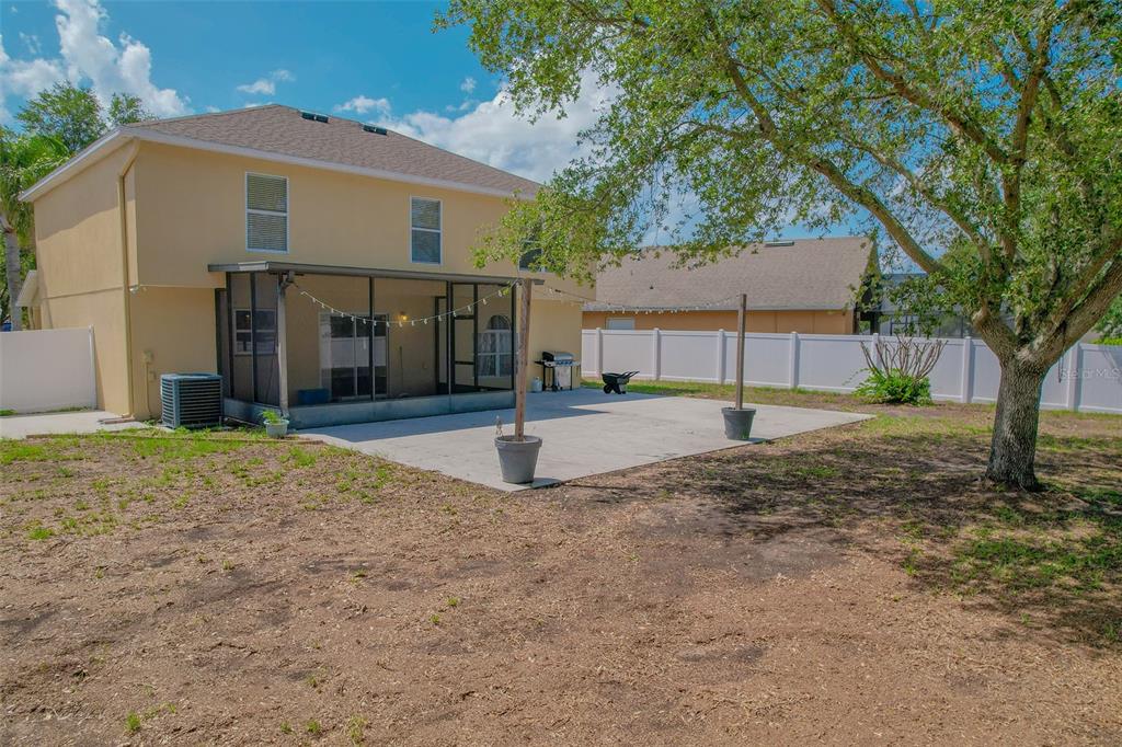 A tan two-story house exterior features a covered entryway with a gray door and palm tree — 2019 HONEYBELL AVENUE, HAINES CITY, FL