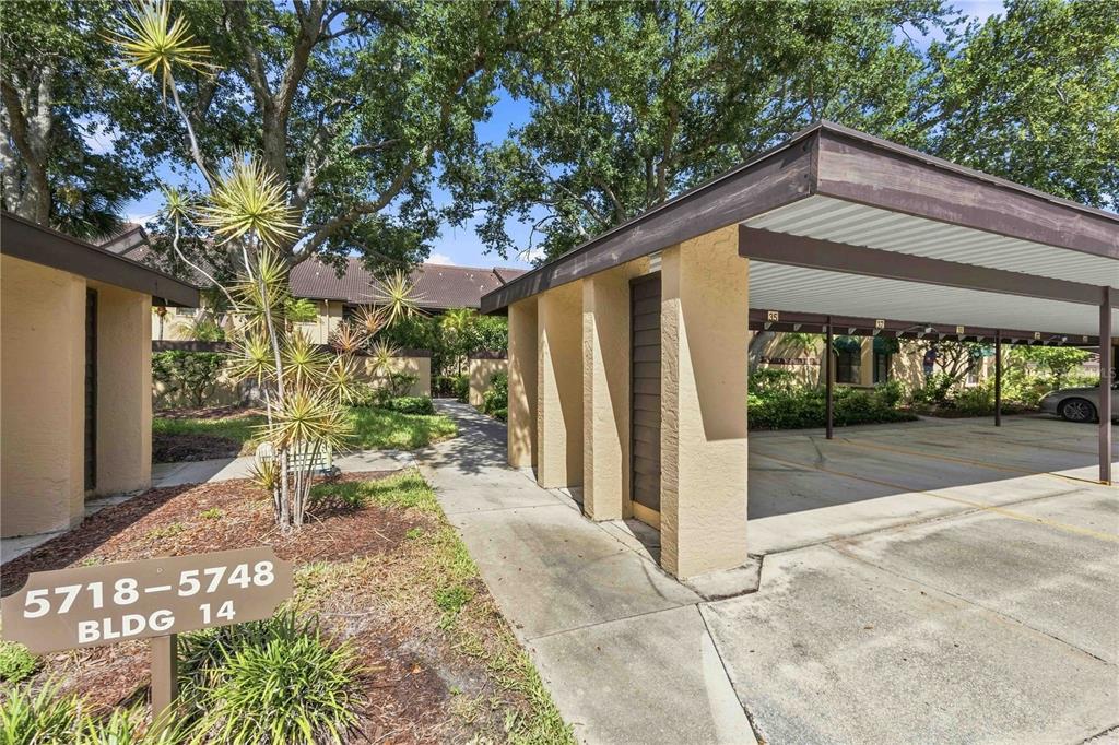 A covered parking structure sits beside a walkway leading to a multi-unit residential building — 5726 ASHTON LAKE DRIVE UNIT 11, SARASOTA, FL