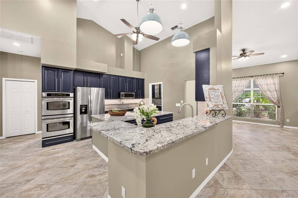 A kitchen with dark blue cabinets, granite countertops, and a breakfast bar in an open room — 19647 SW 93RD PLACE, DUNNELLON, FL