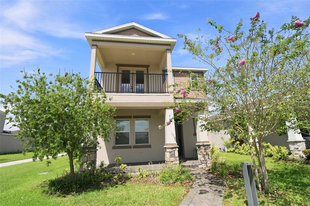 A two-story house with a stone-based porch, a second-floor balcony, and a paved walkway — 761 FIREROCK LANE, DEBARY, FL