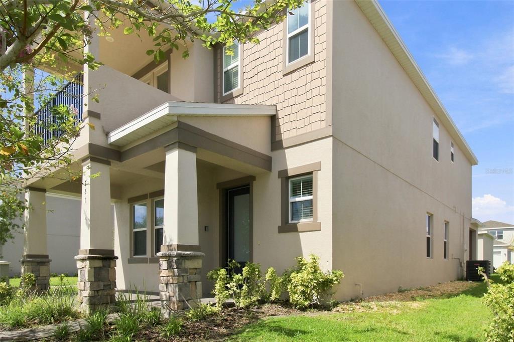 A two-story suburban house with a covered front porch, stone pillars, and tan siding — 761 FIREROCK LANE, DEBARY, FL