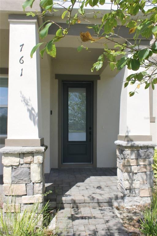 A front entryway features a dark door with a glass panel between two stone-based columns — 761 FIREROCK LANE, DEBARY, FL