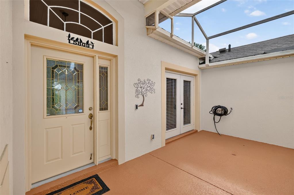 A covered entryway features a front door with a glass insert and double French doors — 5809 BOUNTY CIRCLE, TAVARES, FL
