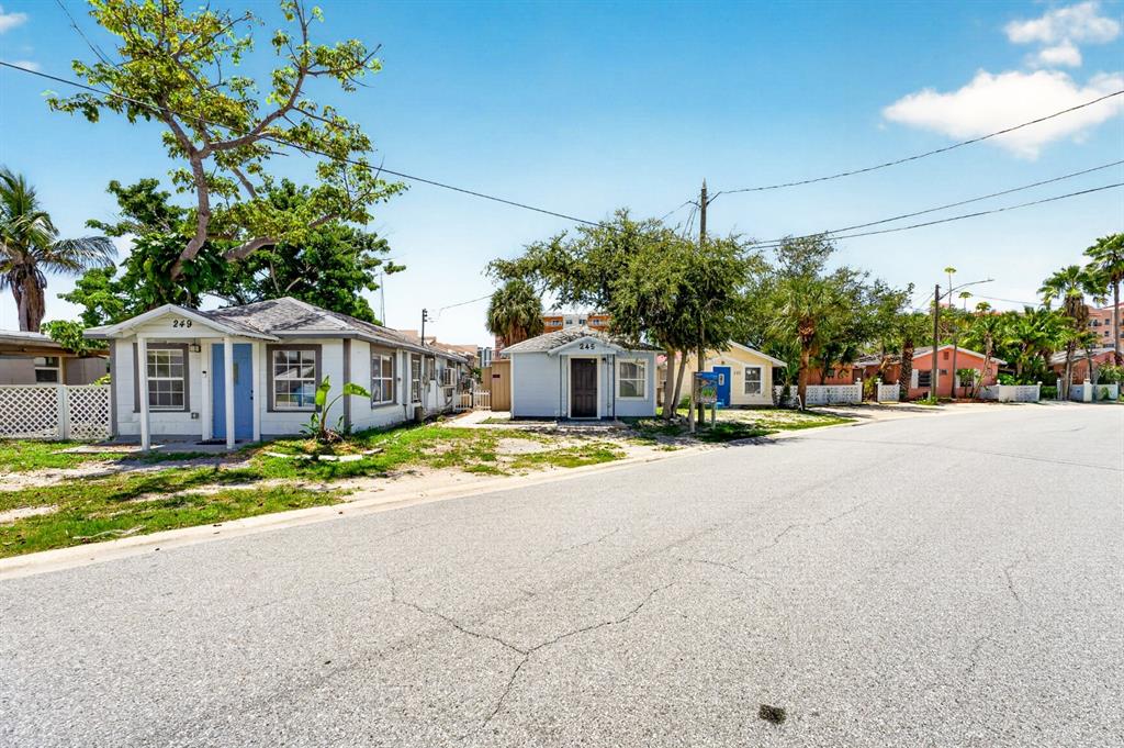 A street view shows several small, single-story houses with light-colored siding and palm trees nearby — 249 BOCA CIEGA DRIVE, MADEIRA BEACH, FL