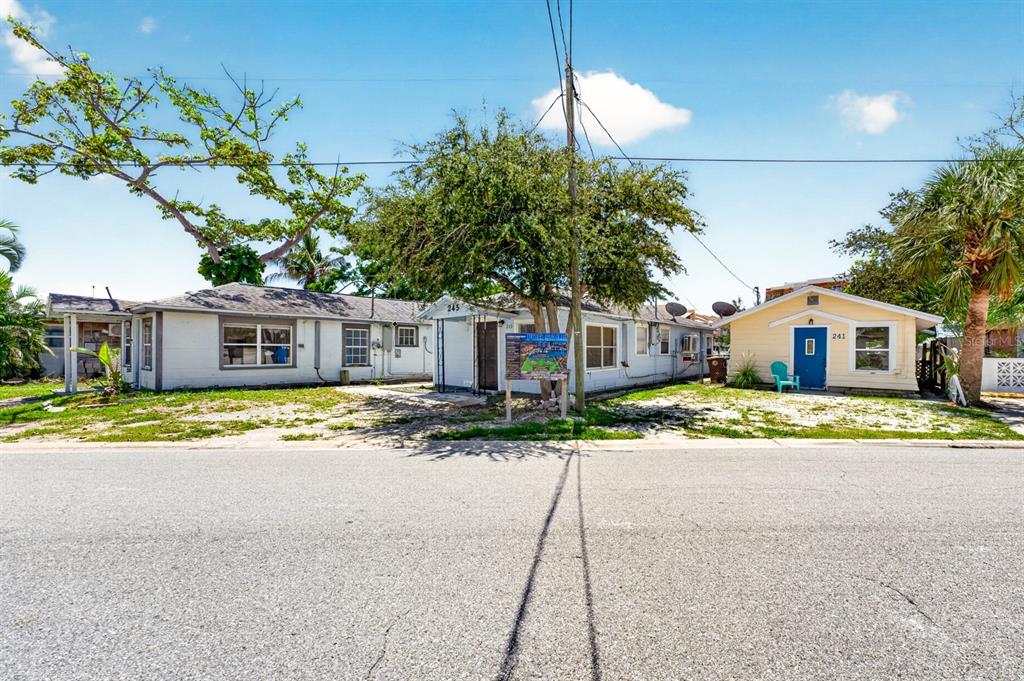 A street-level view of two adjacent single-story houses with a large tree in front — 249 BOCA CIEGA DRIVE, MADEIRA BEACH, FL