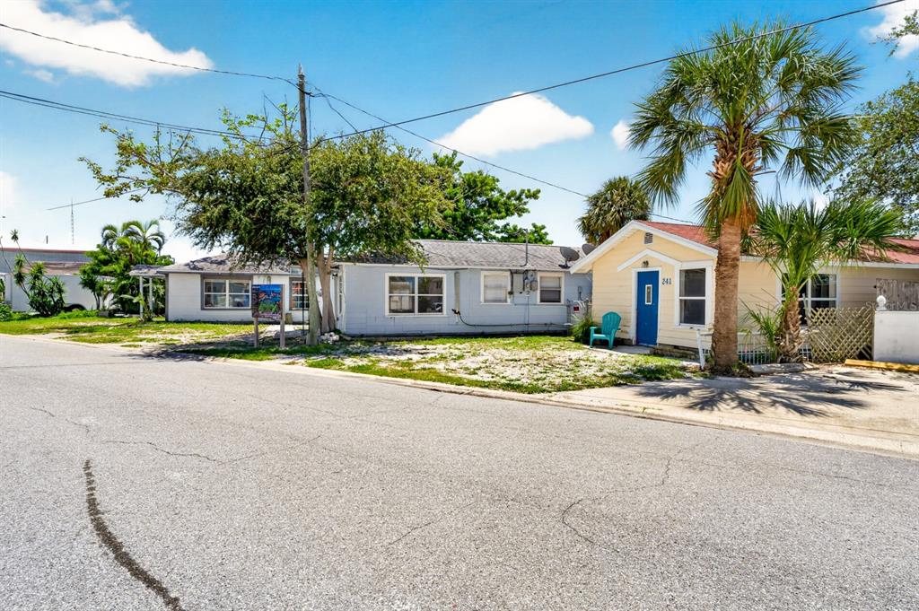 A yellow house with a blue door sits next to a grey house on a street — 249 BOCA CIEGA DRIVE, MADEIRA BEACH, FL