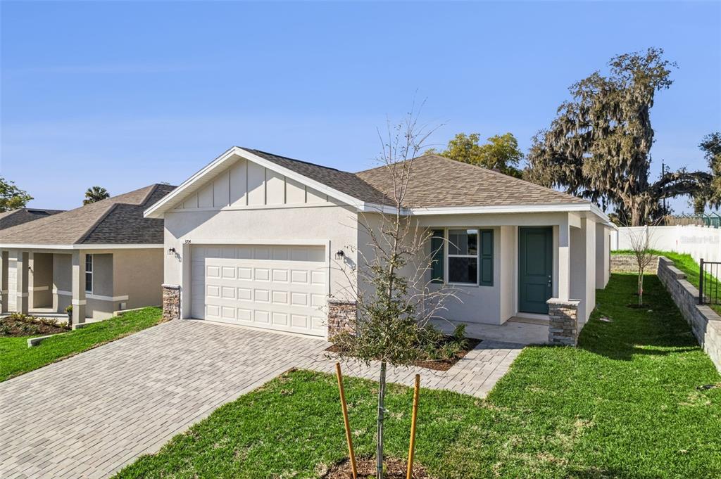A single-story house with a beige stucco exterior, a two-car garage, and a paved driveway — 3780 WATERCLIFF CIRCLE, GRAND ISLAND, FL