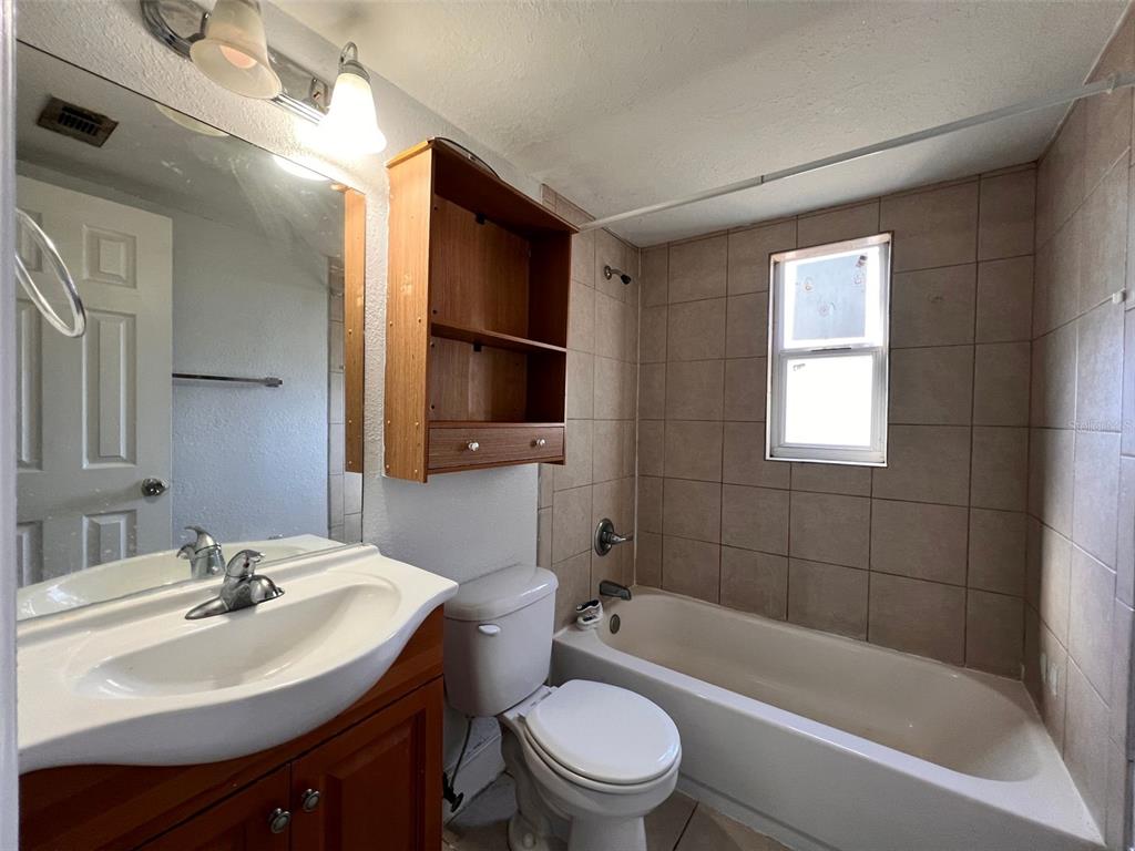 A bathroom features a vanity with a sink, a toilet, and a tiled shower-tub combo — 1710 S WASHINGTON AVENUE UNIT 01, TITUSVILLE, FL