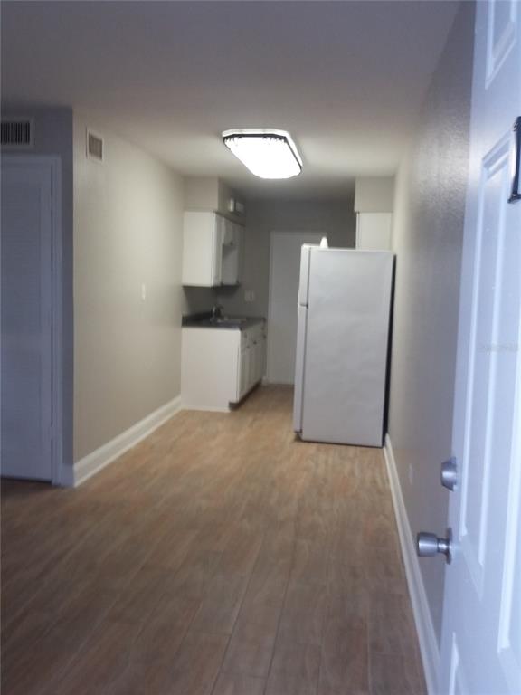 A view from a doorway into a kitchen with light-colored tile flooring and white appliances — 1710 S WASHINGTON AVENUE UNIT 01, TITUSVILLE, FL