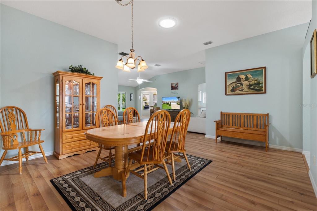 A dining room with a wooden table, chairs, hutch, bench, and light blue walls — 2494 FLINTSHIRE AVENUE, THE VILLAGES, FL