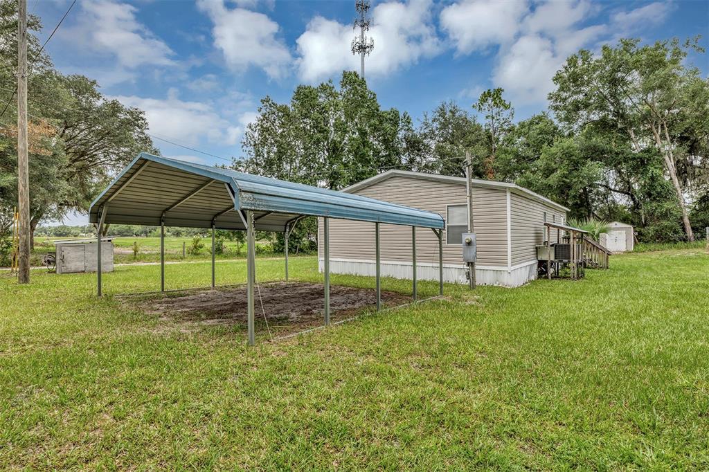 A metal carport stands next to a single-wide mobile home on a grassy lot — 2756 NE 34TH ROAD, COLEMAN, FL