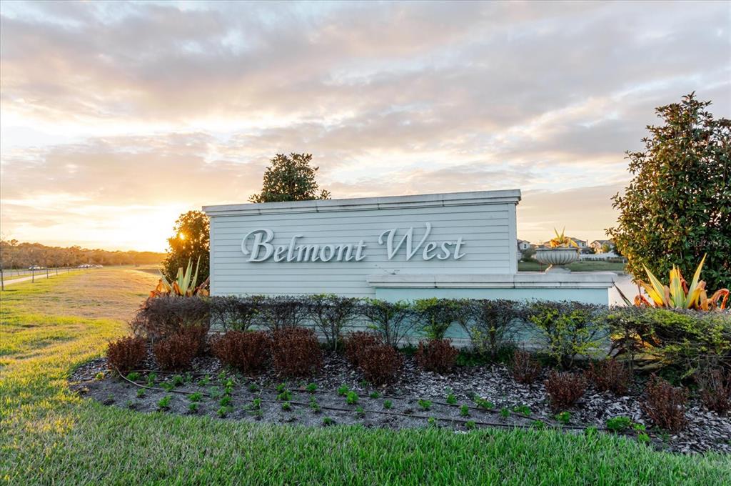 A white neighborhood entrance sign for Belmont West stands in a grassy area at sunset — 9411 LEMON DROP LOOP, SUN CITY CENTER, FL