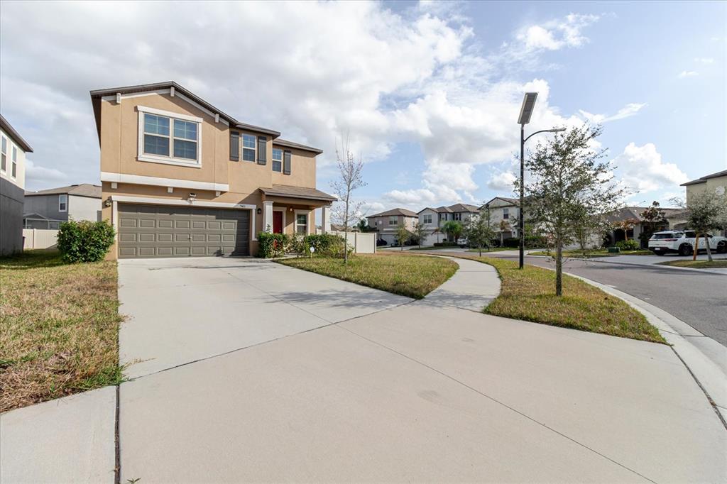 A two-story suburban house with a tan exterior, a two-car garage, and a concrete driveway — 9411 LEMON DROP LOOP, SUN CITY CENTER, FL